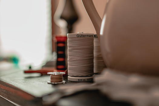 Bobines de fil à coudre sur une table, avec une lumière douce en arrière-plan, évoquant l'artisanat textile.
